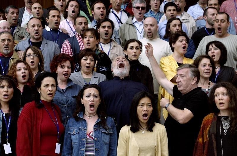 Italian Maestro Gianluigi Gelmetti (C) sings with the Rome Opera Chorus during a visit to the Sydney Opera House February 24, 2004. Gelmetti is the new Chief Conductor and Artistic Director of the Sydney Symphony, and will perform with the touring Italian chorus in a production of Verdi's epic Requiem starting tomorrow night. REUTERS/David Gray DG - RP4DRIGBCZAB