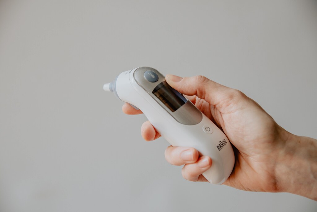 This image shows someone holding a digital thermometer, illustrating the importance of health data