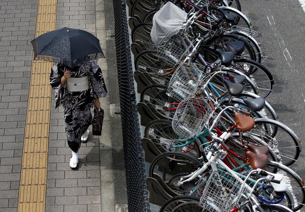 A kimono-clad woman holding a parasol walks next to a cycle parking lot near a railway station in Tokyo, Japan August 29, 2017. REUTERS/Issei Kato
