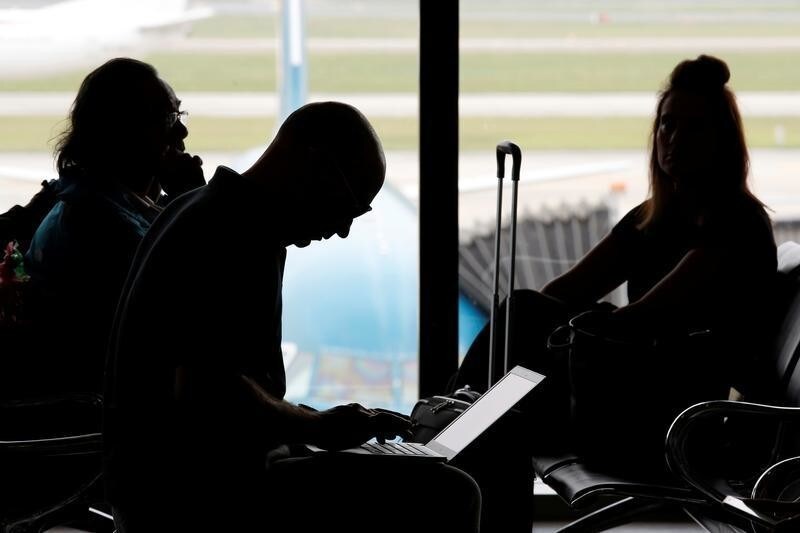 A man (C) works on a laptop at the airport in Hanoi, Vietnam October 18, 2017. REUTERS/Kham - RC11E49AE420