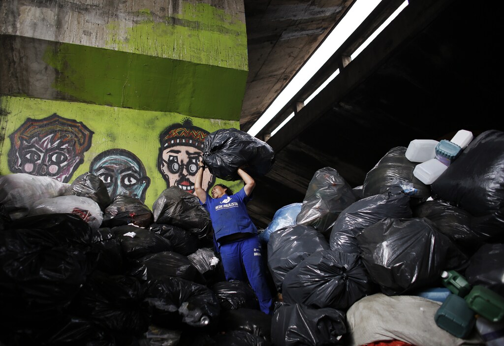 Garbage recycler Marilene Barbosa, 44, throws a bag of trash onto a pile under the Glicerio viaduct in downtown Sao Paulo March 14, 2014. Brazil generates 250,000 tons of waste every day, according to official estimates, and the city of Sao Paulo is the biggest contributor to that with 19,000 tons. Under the Glicerio viaduct, workers known as "catadores" select material to send to recycling centers, amounting up to some 100 tons each month. Picture taken March 14, 2014. REUTERS/Nacho Doce (BRAZIL - Tags: ENVIRONMENT SOCIETY) - GM1EA4N0A4F01