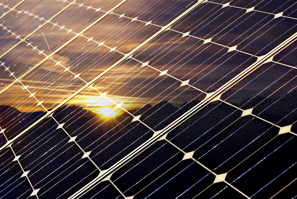 Sunset reflected in solar panels. Integrating AI into solar farms can improve efficiency, and offset some of the vast energy demands that AI places on grids.