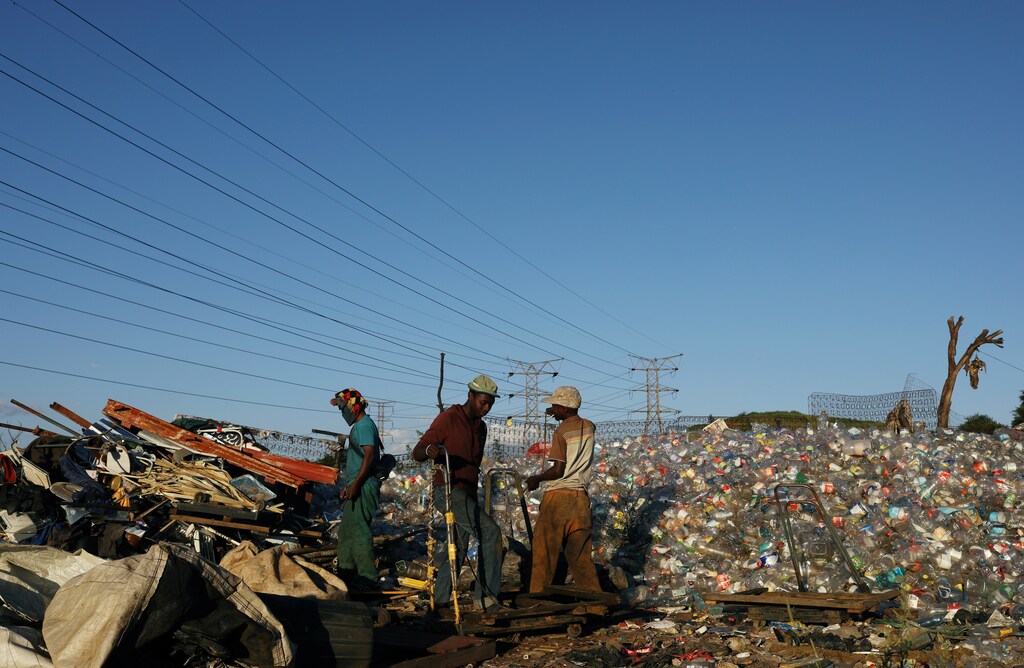 Men sort waste materials including plastic bottles in Soweto, South Africa.