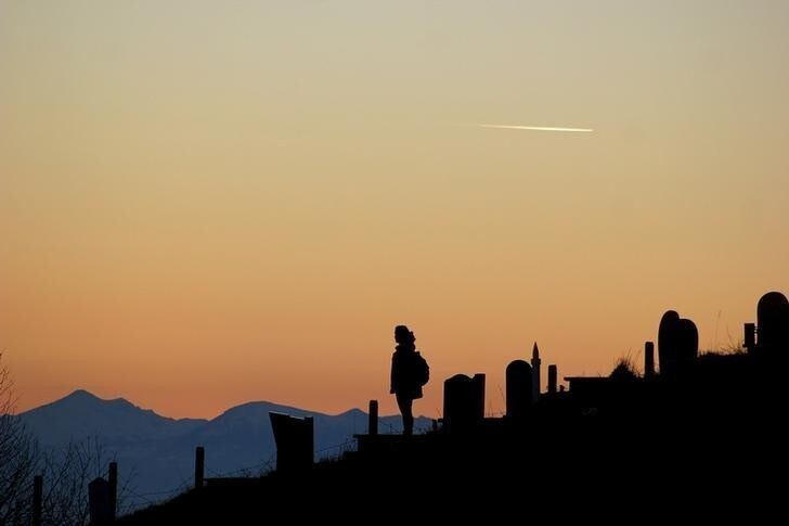 A tourist stands on the martyr cemeteries in the village of Bajgora, northern Mitrovica during sunset December 26, 2015. REUTERS/Agron Beqiri