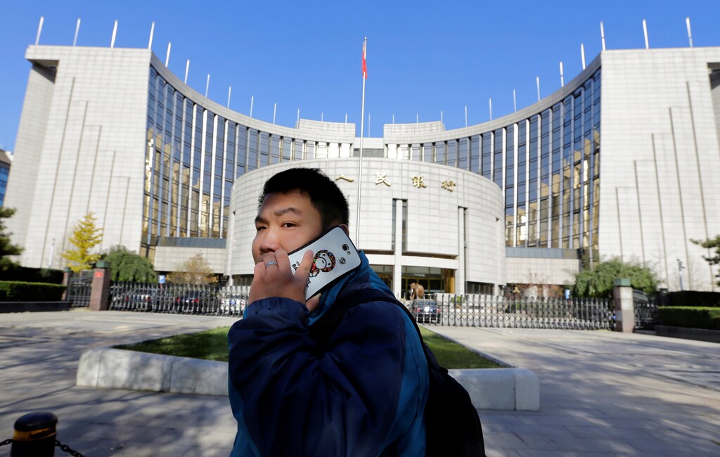 A man uses his mobile phone while walking past the headquarters of the People's Bank of China (PBOC), the central bank, in Beijing, November 20, 2013. REUTERS/Jason Lee/File Photo - RTX2PSUT