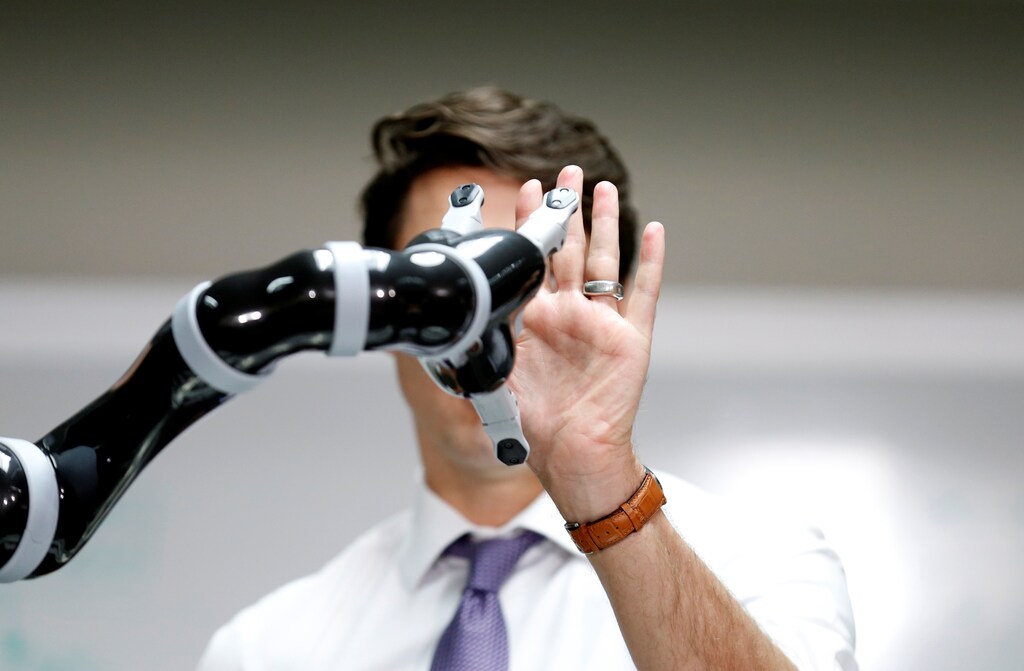 Canadian Prime Minister Justin Trudeau high fives a robotic arm as he takes part in a robotics demonstration at Kinova Robotics in Boisbriand, Quebec, Canada March 24, 2017. REUTERS/Christinne Muschi TPX IMAGES OF THE DAY - RTX32L58