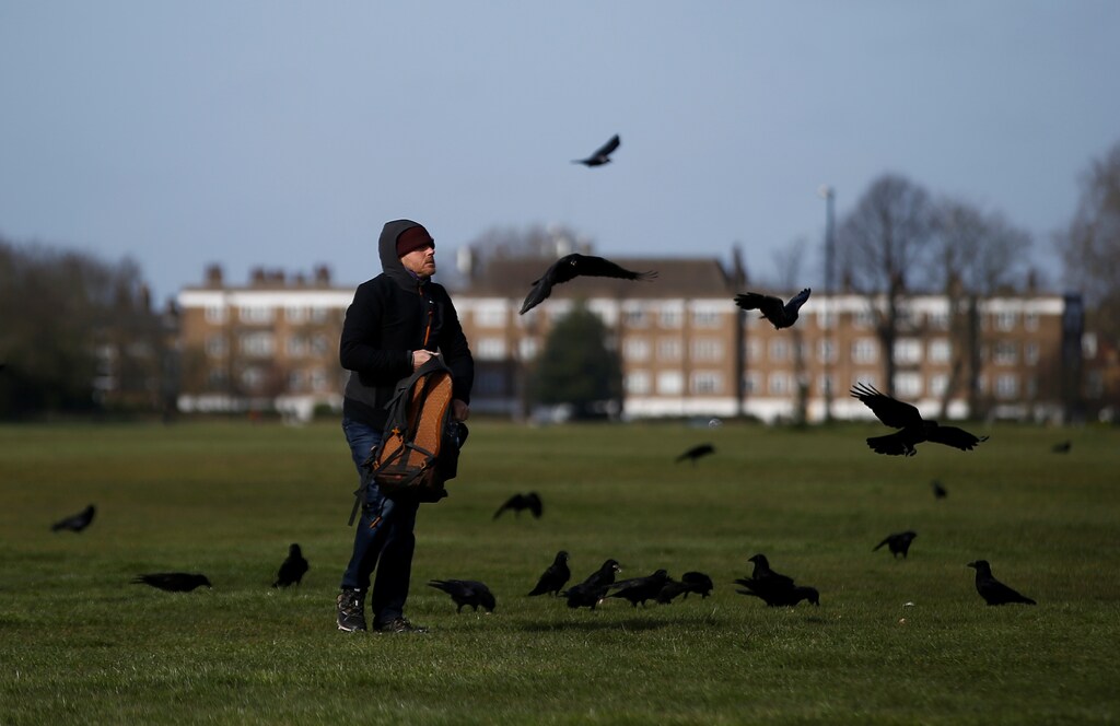 A man feeds some birds on Blackheath Common, as the spread of the coronavirus disease (COVID-19) continues, London, Britain, March 29, 2020. REUTERS/Henry Nicholls - RC2LTF9EDD5D