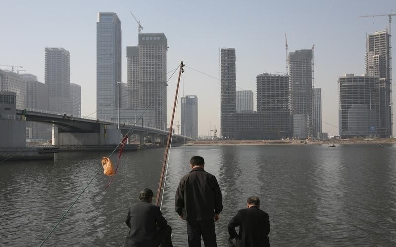 Residents fish with nets on the banks of the Hai River in Tianjin's Binhai New Area, where the government is building its Yujiapu financial center October 23, 2012. The towers in Tianjin's Yujiapu Financial District, and two dozen others on the opposite side of the river, are monuments to the transformation of this once-rundown northern city of 13 million into the country's fastest growing region last year. Picture taken October 23, 2012. REUTERS/Michael Martina (CHINA - Tags: BUSINESS POLITICS CONSTRUCTION) - RTR39ZT3