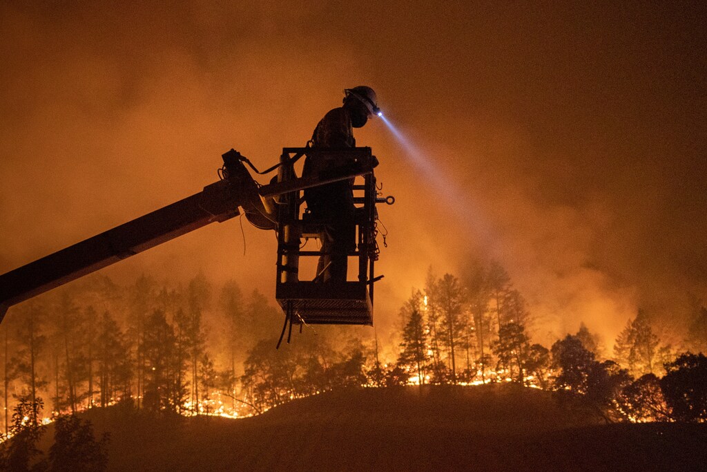 The Glass Fire burns in the background as Josh Asbury, an employee of CableCom, installs fiber optic cable in Calistoga, California, U.S. September 28, 2020. REUTERS/Adrees Latif - RC2JYK99DKXZ