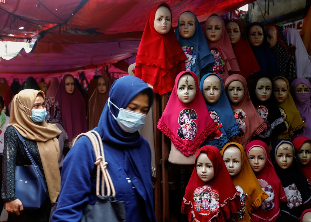 Women walk past hijabs displayed for sale at the Tanah Abang textile market in Jakarta, Indonesia, March 16, 2021.