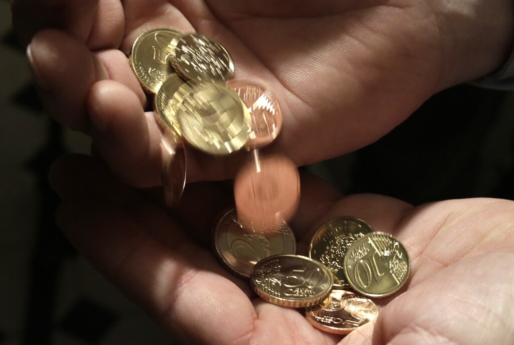 A man holds Latvian euro coins during a central bank presentation of a citizen startup kit in Riga December 9, 2013. Latvia will join the euro zone on January 1, 2014. REUTERS/Ints Kalnins (LATVIA - Tags: BUSINESS) - RTX16BCZ