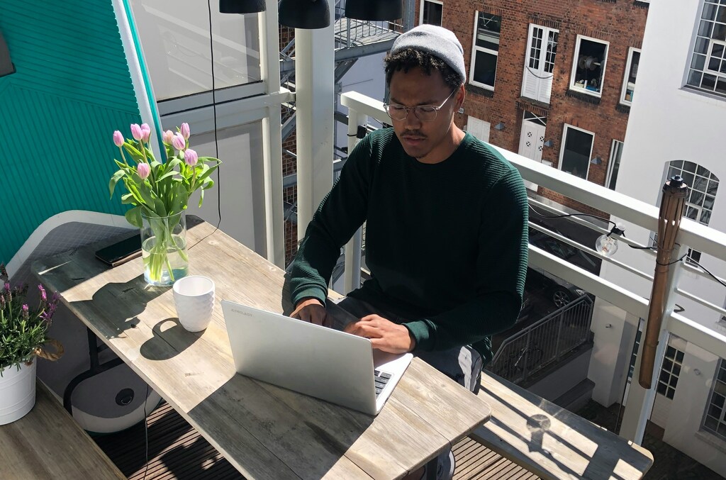 Man in long sleeve top on laptop on rooftop: Digital nomads can bring in more spending to the local economy in Japan.