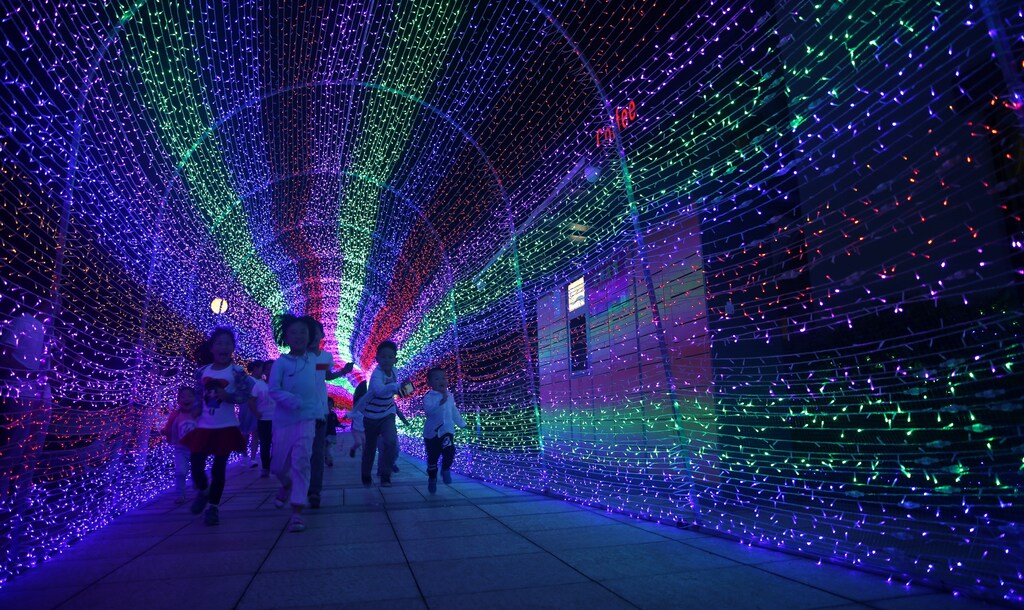 Children pose for cameras at a lantern installation during a lantern show in Quzhou, Zhejiang Province, China, May 25, 2016.