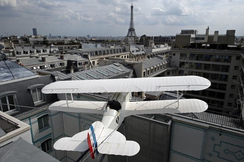 A seventy five percent size replica of the L'Oiseau Blanc biplane is seen on the terrace of the restaurant and bar L?Oiseau Blanc located on the sixth floor of the the Peninsula Paris luxury hotel in Paris July 30, 2014. After four years of refurbishment work costing 430 million euros, the Peninsula Paris hotel opens its doors on Friday, promising prince-like treatment to well-heeled visitors to the French capital. The new hotel located in a 1908 building a stone's throw from the Arc de Triomphe and Champs Elysees, will offer rooms starting a just over 1,000 euros a night and rising to 25,000 euros for a penthouse suite with its own roof-top garden. Each of its 200 rooms allows guests to make free phone calls anywhere in the world and is fitted with a printer, coffee machine, a nail-dryer and a tablet centralising all functions from dimming the lights to ordering breakfast. On the background the Eiffel Tower. Picture taken July 30, 2014. REUTERS/Benoit Tessier (FRANCE - Tags: BUSINESS TRAVEL) - RTR40THC