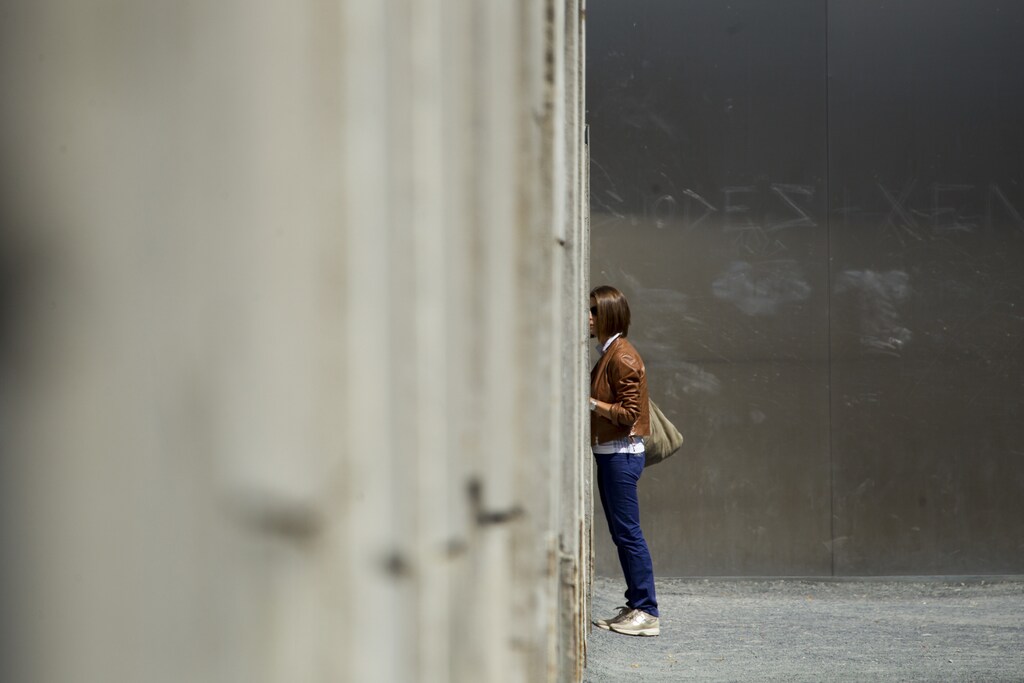 A woman looks through a crack in a concrete barrier that is part of the former Berlin Wall border fortification at the memorial site in Bernauer Strasse in Berlin, August 13, 2012.
