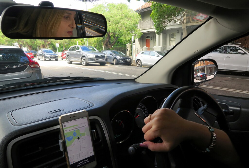 Rosalina Kariotakis, President of the Ride Share Drivers' Association of Australia, is reflected in a mirror as she drives her car she uses for the ride services company Uber along a street in central Sydney, Australia, March 31, 2017. REUTERS/David Gray - RC138E0772D0