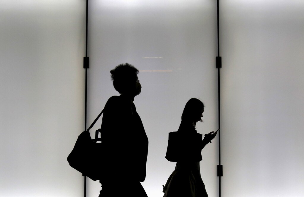 A man and a woman are silhouetted as they walk on an overpass at a business district in Tokyo, Japan, November 5, 2015. REUTERS/Yuya Shino - GF20000046606