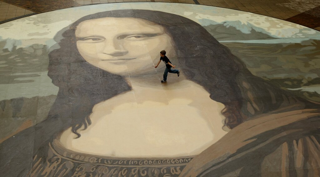 A boy runs across a giant copy of the Mona Lisa as it is unveiled in Wrexham, north Wales, October 28, 2009. The giant version of Leonardo da Vinci's masterpiece measuring 17.5 metres across and 50 times bigger than the original, is an attempt to produce the largest ever reproduction of the painting. REUTERS/Phil Noble (BRITAIN ENTERTAINMENT SOCIETY) - GM1E5AS1ENG01