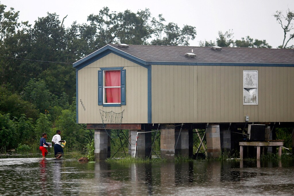 Residents walk through flood water back to their raised house during Hurricane Barry in Plaquemines Parish, Louisiana, U.S. July 14, 2019. REUTERS/Jonathan Bachman - RC1A257089E0