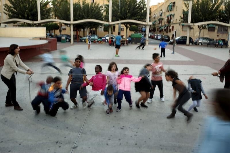 ATTENTION EDITORS: SPANISH LAW REQUIRES THAT THE FACES OF MINORS ARE MASKED IN PUBLICATIONS WITHIN SPAIN Spanish childhood educators Eva Molina, 37, (R), Raquel Lopez, 24, (L) and children play at a square while attending a programme that gives children academic and psychological help to improve their chances in life, outside a Catholic charity Caritas centre in the neighborhood of Puente Tocinos, near Murcia, southeast Spain, November 3, 2015. Spain is facing rising levels of child poverty as its economic recovery fails to bridge a growing gulf between rich and poor, storing up problems for an already-strained social security system. While the country has emerged from recession and become one of the fastest-growing economies in Europe, more than one in three children - or 2.6 million - are at risk of poverty or social exclusion, according to latest EU figures. Picture taken November 3, 2015. REUTERS/Jon Nazca - GF20000057698