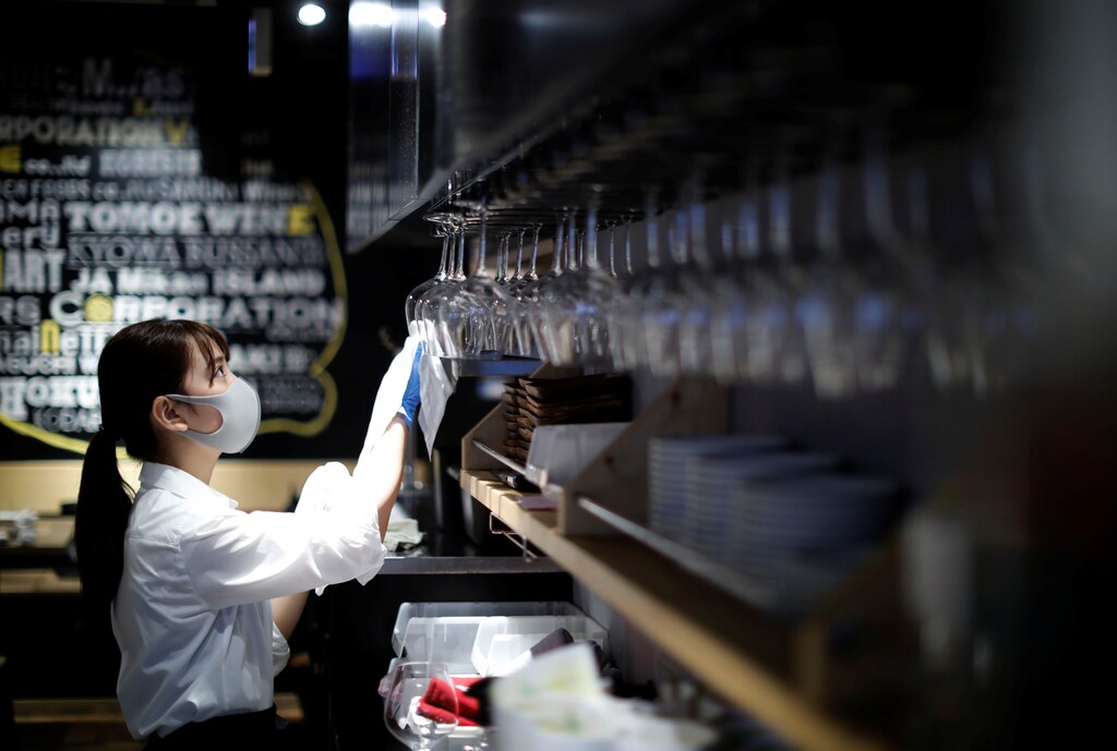 A waitress wearing a protective mask and gloves amid the coronavirus disease (COVID-19) outbreak, cleans glasses at Setouchi Lemon Shokudo in Tokyo, Japan June 22, 2020. Picture taken June 22, 2020. REUTERS/Kim Kyung-Hoon - RC20GH941KMO
