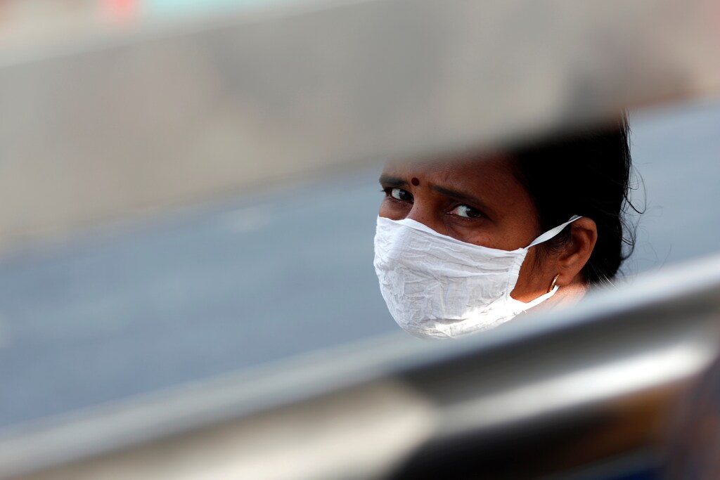 A woman wearing a protective mask waits for a bus to return to her village during lockdown by the authorities to limit the spreading of coronavirus disease (COVID-19), in New Delhi, India March 23, 2020