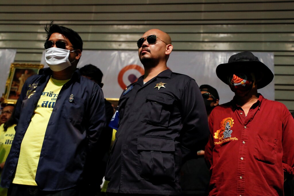 People, some wearing protective masks, look on as members of Thai right-wing group "Thai Pakdee" (Loyal Thai) attend a rally in support of the government and the monarchy and in opposition to the recent anti-government protests, in Bangkok, Thailand August 30, 2020. REUTERS/Jorge Silva - RC2AOI9LOBU1