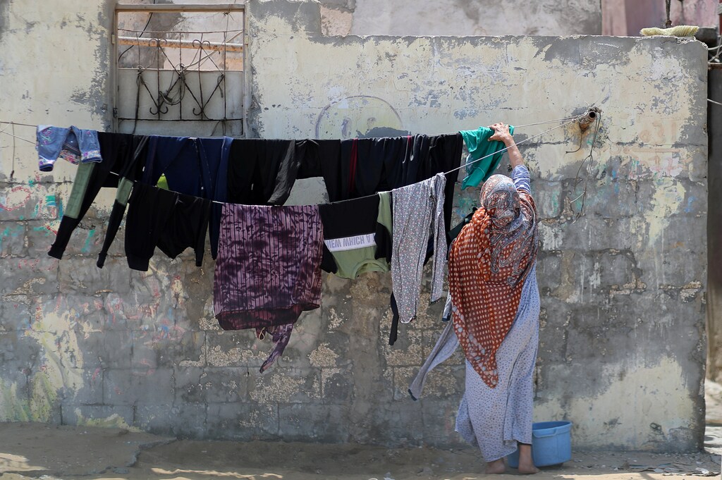 A Palestinian woman hangs laundry to dry outside her house at the Beach refugee camp in Gaza City June 18, 2020. Picture taken June 18, 2020. REUTERS/Mohammed Salem - RC27CH9J3R1S
