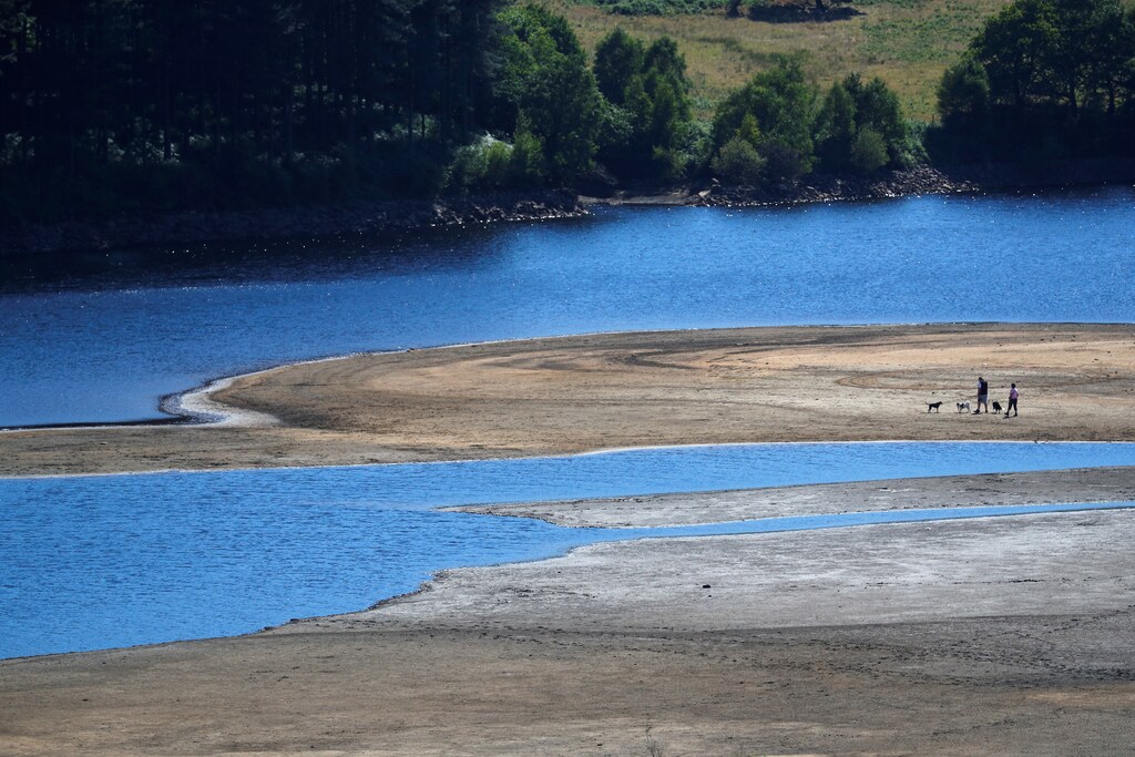 Two people take a walk near the water's edge, where the water level has dropped significantly during the U.K. heatwave, of Torside Reservoir in Longdendale, Derbyshire, Britain, July 3, 2018. REUTERS/Phil Noble - RC1ED66CB150
