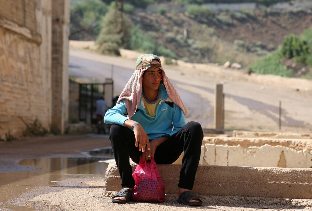 A youth rests with a towel on his head after swimming in Glen river, in Deraa Governorate, Syria June 25, 2016. REUTERS/Alaa Al-Faqir - RTX2I6NG