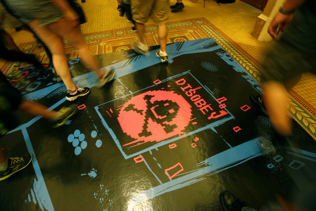 People walk past a floor graphic during the Def Con hacker convention in Las Vegas, Nevada, U.S. on July 29, 2017. REUTERS/Steve Marcus - RC1B13C62450