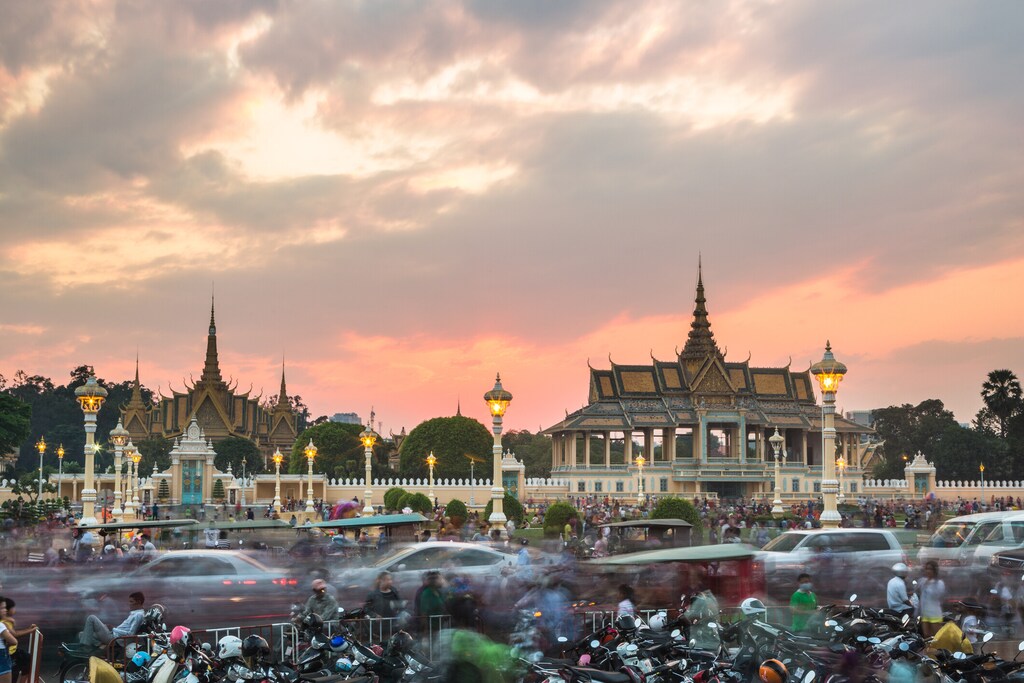 Phnom Penh, Cambodia - January 24, 2016: Cars and motorcycles rush in front of the Royal Palace at sunset in Cambodia capital city. Sustainable transport in Asia.