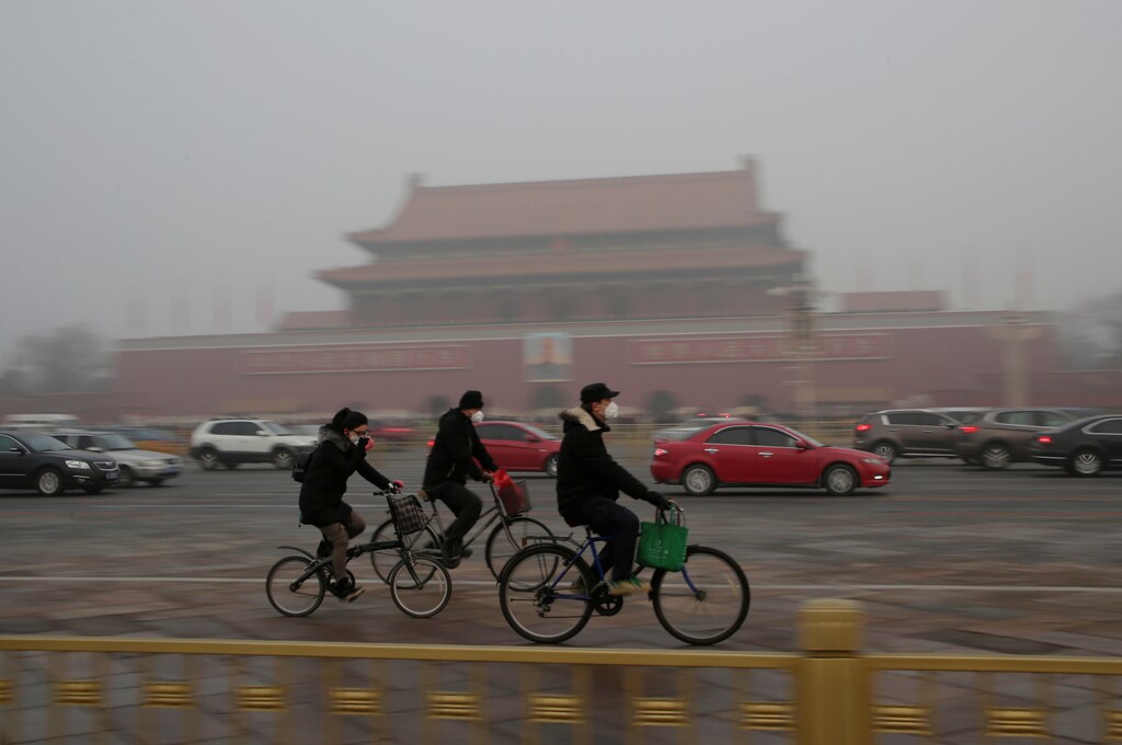 People wearing masks cycle past Tiananmen Gate during the smog after a red alert was issued for heavy air pollution in Beijing, China, December 20, 2016. REUTERS/Jason Lee - RTX2VRP0