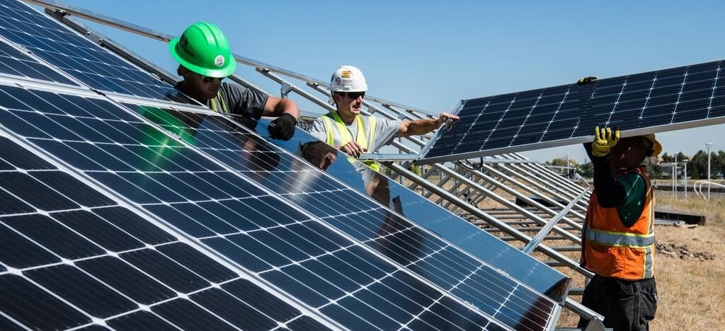 Three men install solar panels.