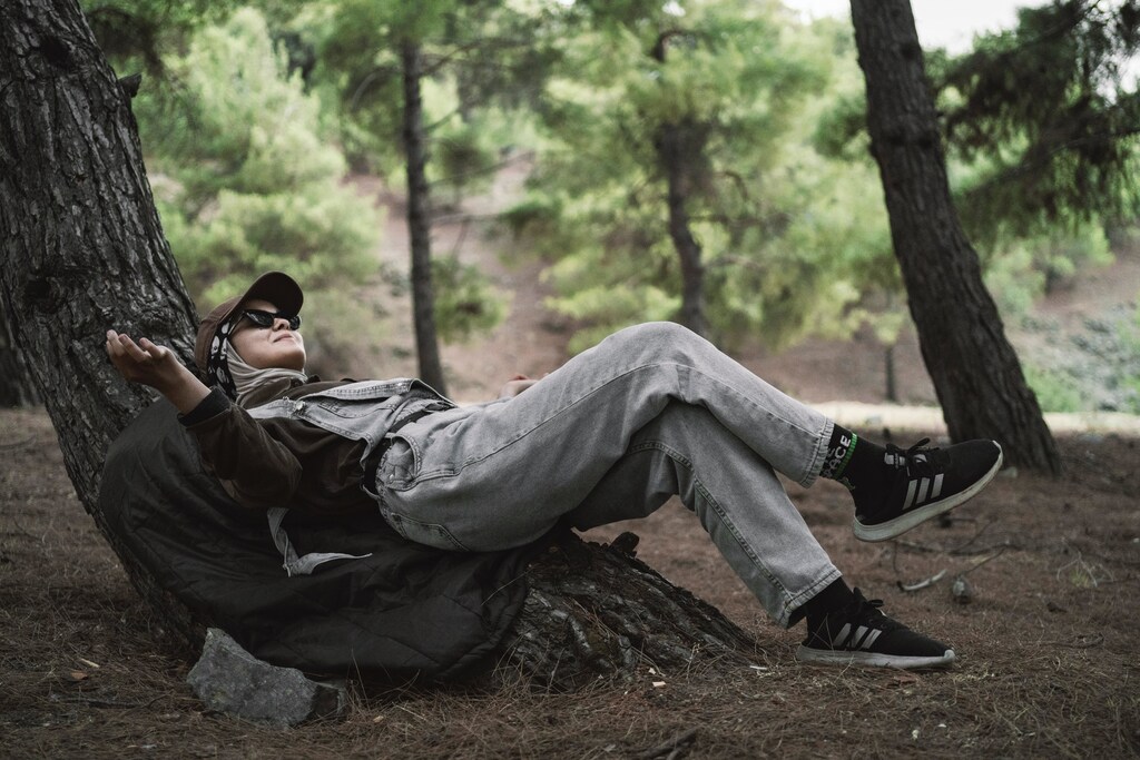 A woman relaxing on a tree in the middle of a woods.