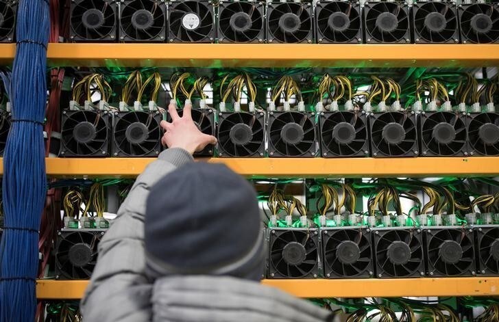 A worker checks the fan on a miner, at the cryptocurrency farming operation, Bitfarms, in Farnham, Quebec, Canada, February 2, 2018. Picture taken February 2, 2018. REUTERS/Christinne Muschi
