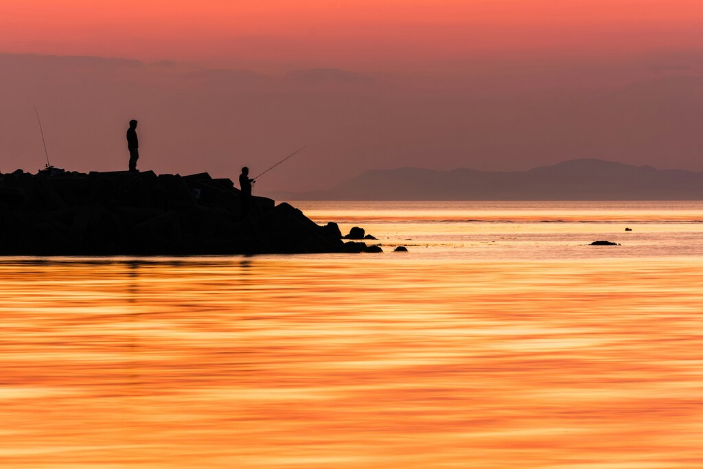 Silhouette of man fishing against a sunset on an island in the Sento Inland Sea: Art festivals can revitalize different business sectors in ageing and depopulated rural communities.