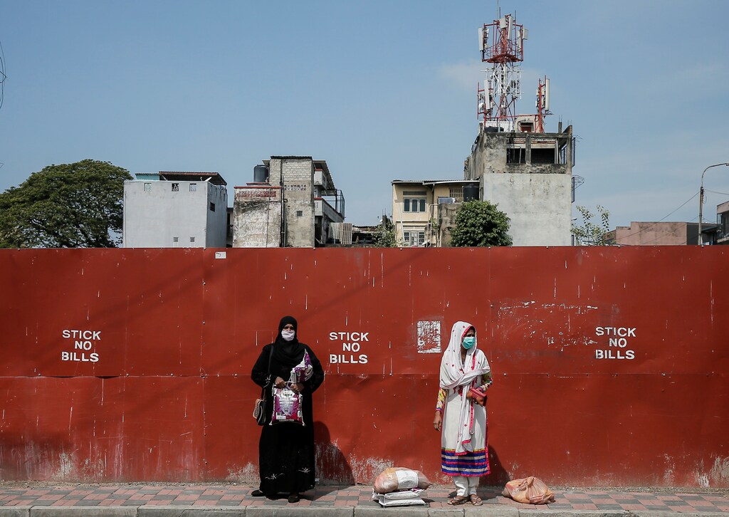 Two Muslim women wearing protective masks stand on a side of the main road after receiving free food items from Sri Lankan Air-force during the curfew, 1 April 2020.