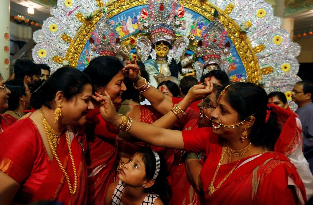 A girl watches as Hindu women apply "sindhur", or vermillion powder, on each others face after worshipping the idol of the Hindu goddess Durga on the last day of the Durga Puja festival in Kolkata, India October 11, 2016. REUTERS/Rupak De Chowdhuri
