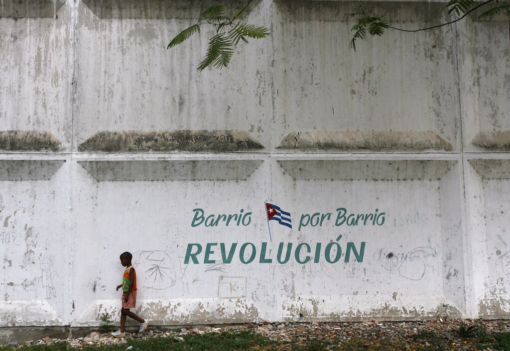 A boy walks past graffiti in Santiago de Cuba July 25, 2008. President Raul Castro returns to the birthplace of the Cuban revolution this week for a speech that will be watched for news on what some consider another, quieter revolution now taking place on the socialist island. Castro's speech, to be given in the eastern city of Santiago on Saturday, will mark the 55th anniversary of the July 26, 1953 rebel assault which Fidel Castro led on the nearby Moncada army barracks. The graffiti reads, "Neighborhood for neighborhood, revolution". REUTERS/Claudia Daut (CUBA) - RTX84UV