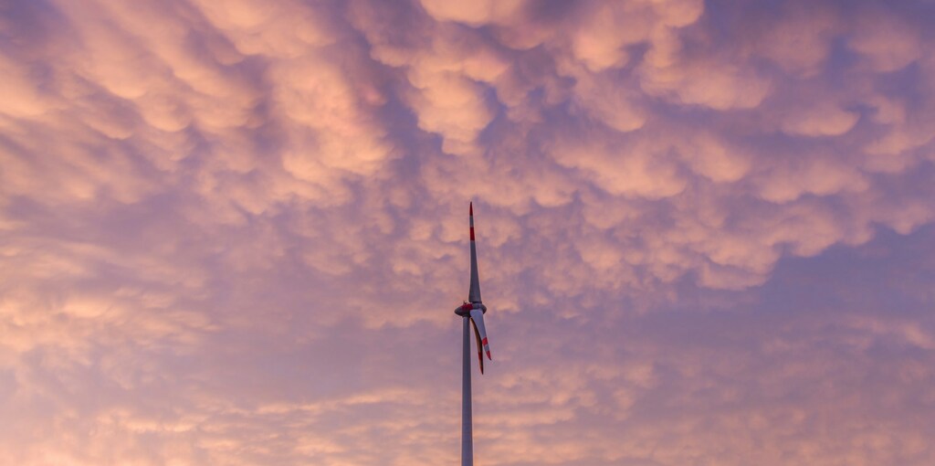 Un cielo con un molino de viento en el medio. La transición a la energía verde tiene que ser justa en todos los ámbitos, pero la inteligencia artificial y la geopolítica podrían cambiar las reglas del juego.