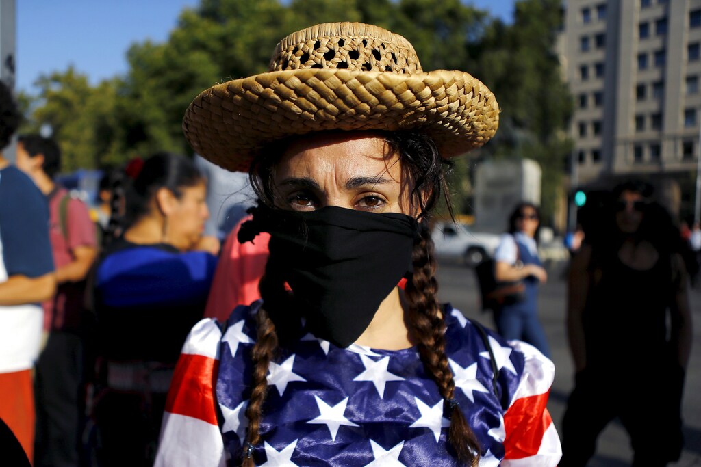 An activist depicting a farmer wears a U.S. flag during a rally against the Trans-Pacific Partnership (TPP) trade deal in front of the government house at Santiago, Chile, February 4, 2016. REUTERS/Ivan Alvarado - RTX25IWJ