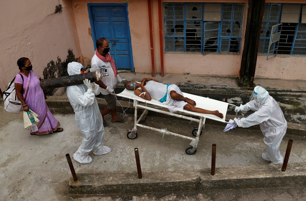 Sameer, 22, a medical worker, carries an oxygen cylinder on his shoulder as COVID-19 patient Parsada Sah, 67, a shopkeeper, is carried on a stretcher by his son Manoj Kumar Sah, 45, and Sameer's colleague as Parsada Sah is transferred from the emergency ward to the Intensive Care Unit (ICU) of Jawahar Lal Nehru Medical College and Hospital, during the coronavirus disease (COVID-19) outbreak, in Bhagalpur, Bihar, India, July 27, 2020. Even though Sah's family know that he is infected, the family goes inside the ward to feed Sah. "The staff just puts the food on the bed; they don't feed anyone," Manoj says. "If the patient can't eat himself, he has to get someone to help." REUTERS/Danish Siddiqui TPX IMAGES OF THE DAY SEARCH "BHAGALPUR HOSPITAL COVID-19" FOR THIS STORY. SEARCH "WIDER IMAGE" FOR ALL STORIES. - RC2NCI95IMTK