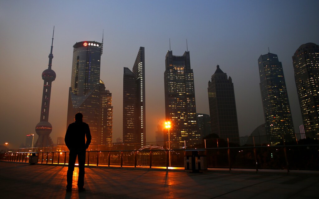 A man looks at the Pudong financial district of Shanghai November 20, 2013. With a shift in tone and language, China's central bank governor has dangled the prospect of speeding up currency reform and giving markets more room to set the yuan's exchange rate as he underlines broader plans for sweeping economic change. The central bank under Zhou Xiaochuan has consistently flagged its intention to liberalise financial markets and allow the yuan to trade more freely, even before the Communist Party's top brass unveiled late last week the boldest set of economic and social reforms in nearly three decades. REUTERS/Carlos Barria (CHINA - Tags: BUSINESS CITYSCAPE TPX IMAGES OF THE DAY) - RTX15LH0