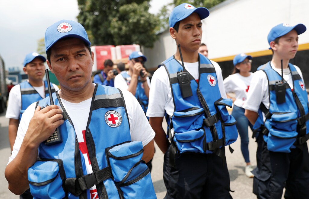 Workers of Venezuelan Red Cross stand next to trucks with logo of the International Federation of Red Cross and Red Crescent Societies (IFRC) carrying humanitarian aid, at a warehouse where the aid will be stored, in Caracas, Venezuela, April 16, 2019. REUTERS/Carlos Garcia Rawlins - RC1BA52F6660