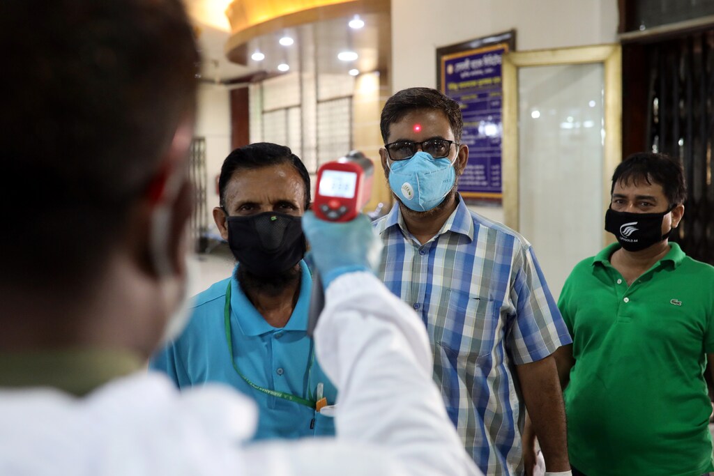A security personnel checks the body temperature of customers with a thermal scanner at the entrance to a bank amid the coronavirus disease (COVID-19) outbreak in Dhaka, Bangladesh, April 2, 2020. REUTERS/Mohammad Ponir Hossain - RC2CWF99V9I9