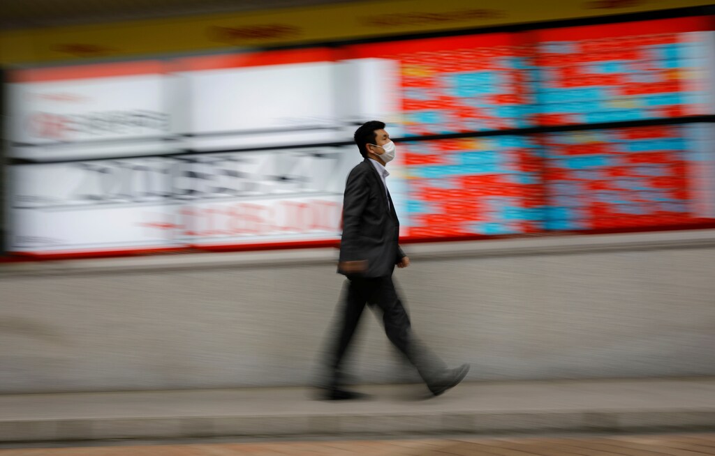 A man wearing a protective face mask, following the coronavirus disease (COVID-19) outbreak, walks in front of a stock quotation board outside a brokerage in Tokyo, Japan, May 18, 2020. REUTERS/Kim Kyung-Hoon - RC2VQG993WL3