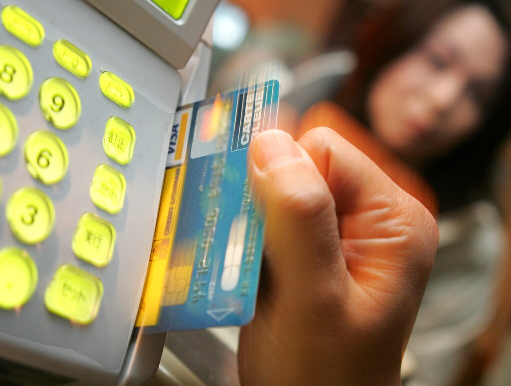 An employee swipes a customer's credit card through the card reader at a restaurant in Tokyo February 19, 2005.