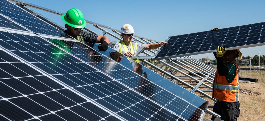 workers fit solar panels into an open field