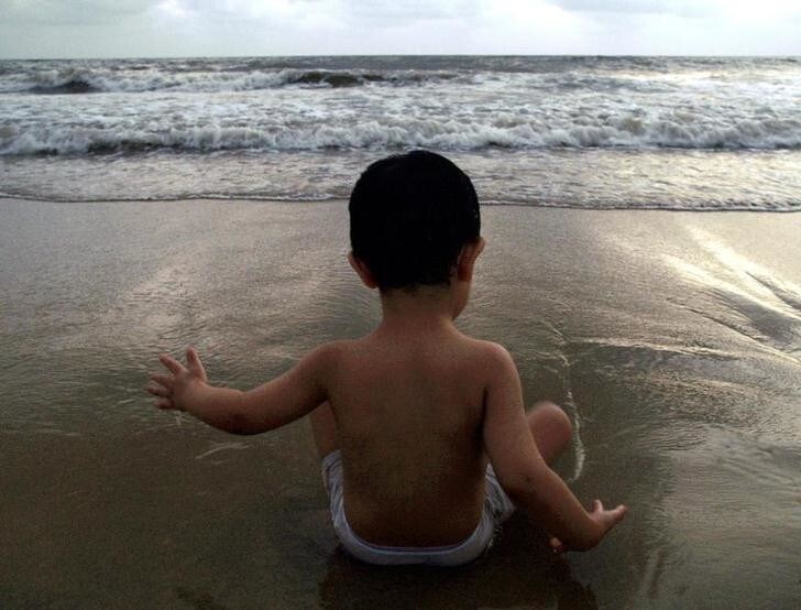 A two-year-old boy cools himself off at a beach in Mumbai May 5, 2006. With the summer temperatures reaching upto 37 degrees Celsius (99 Fahrenheit) people resort to different ways to cool themselves off. REUTERS/Adeel Halim